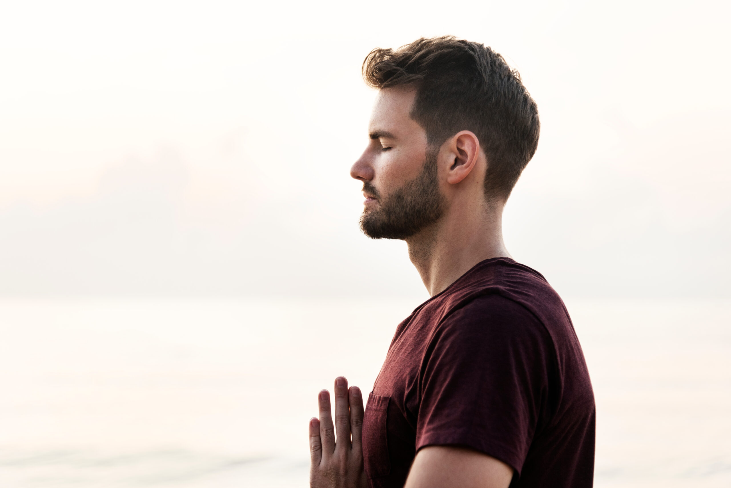 Man practicing yoga and gratitude meditation on the beach