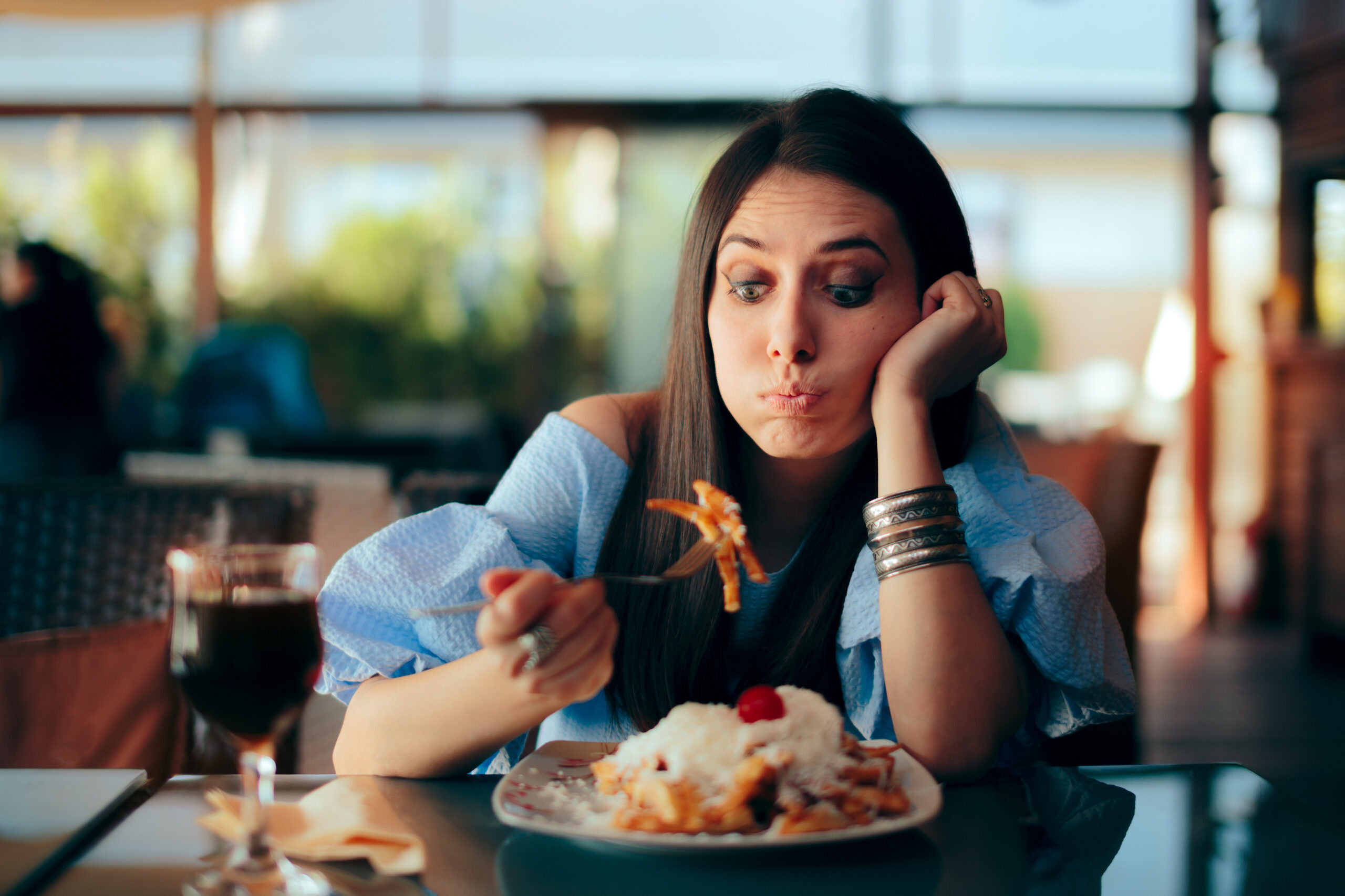 Woman Feeling Sick While Eating Huge Meal. Person experiencing overeating side effects at lunch