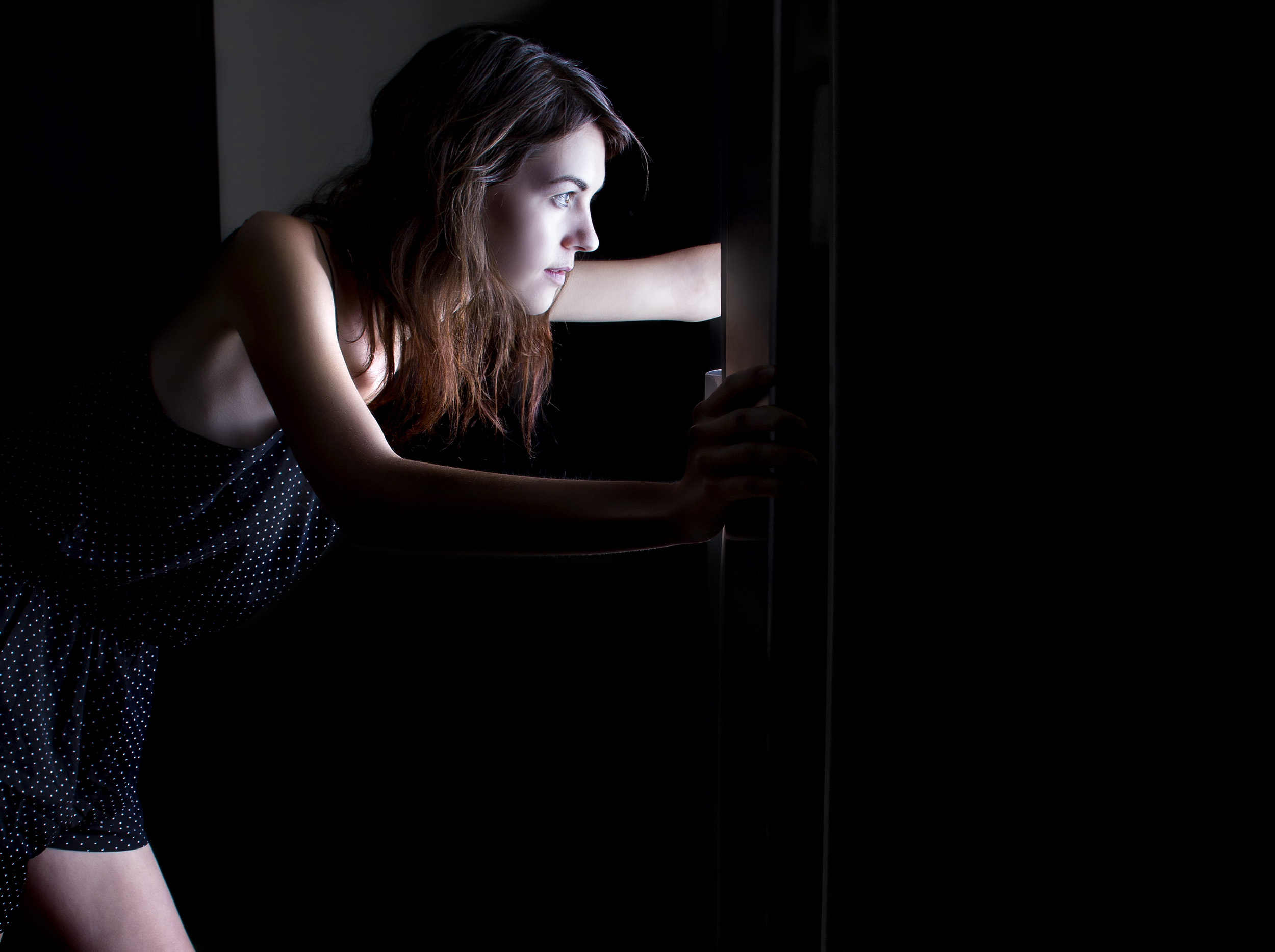 Woman craving and looking for food in an empty fridge late at night. The image is shot low key to depict night time.