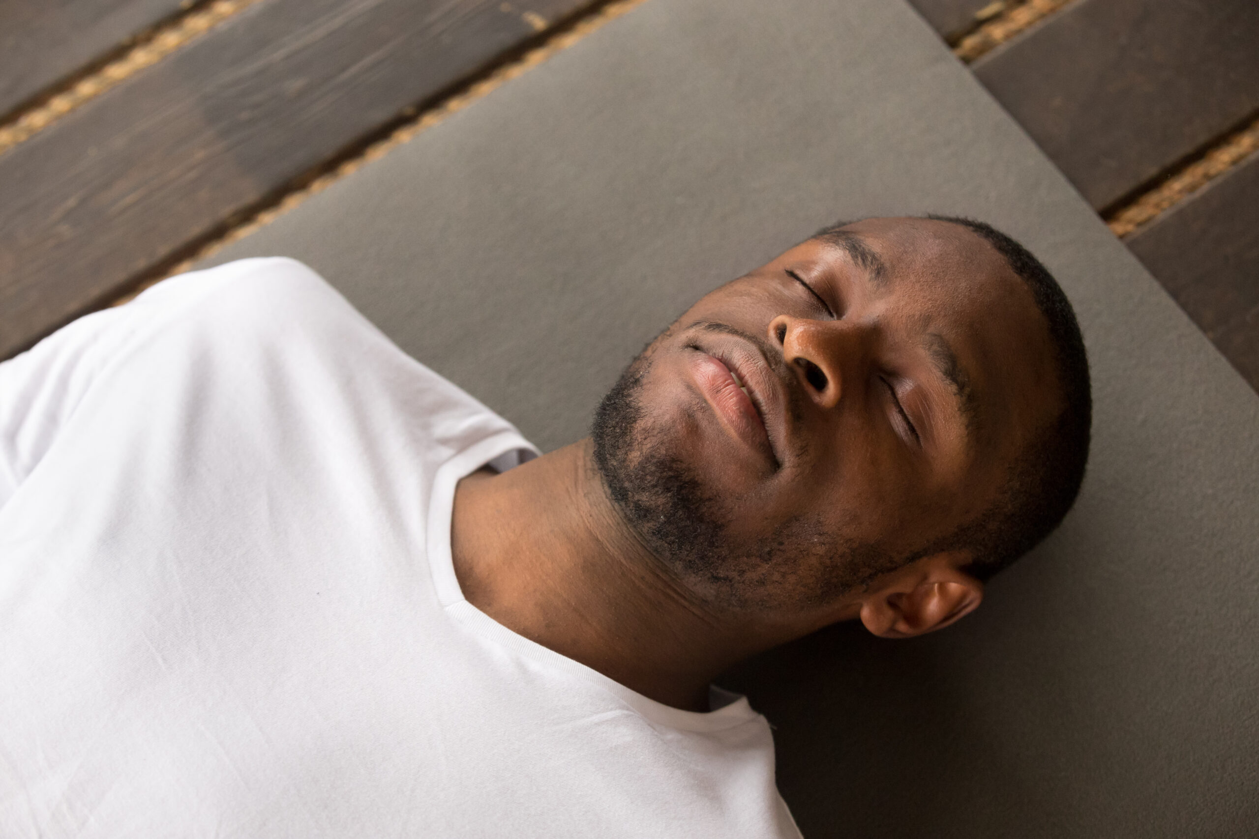 breath work for fasting Photo of young black man lying in reclining exercise restorative pose with his eyes closed, Savasana pose, working out, resting after practice, close up, studio, top view. Healthy lifestyle