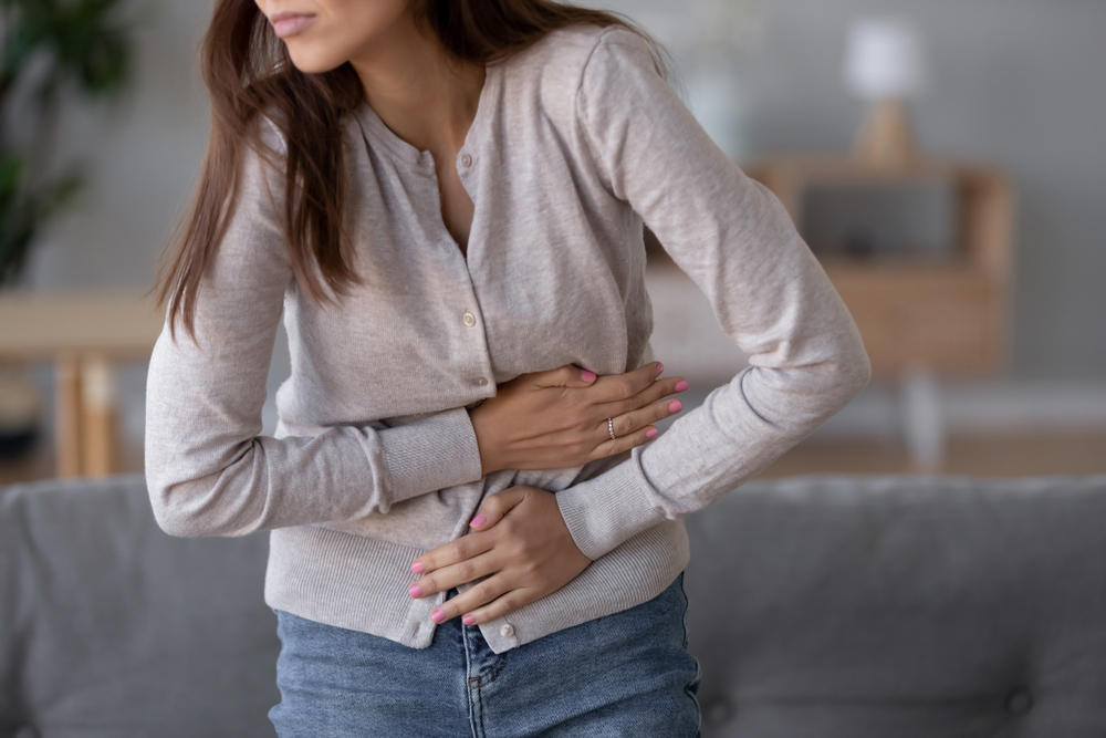 Fasting is great for Gut health--young sick woman standing holding belly suffering from stomach pain feeling painful discomfort hurt abdomen ache having pancreatitis problem, eating disorder, indigestion symptom
