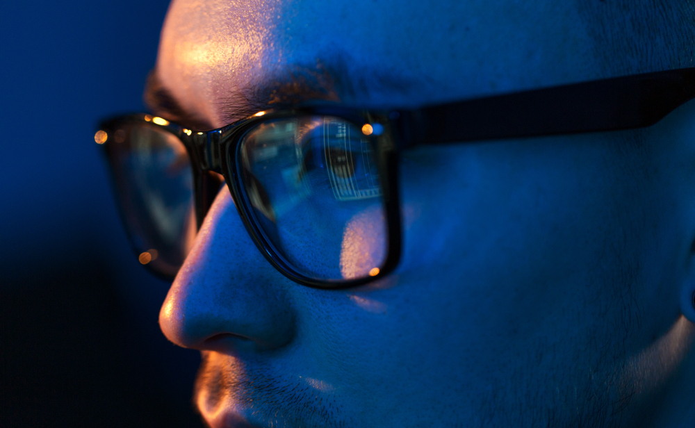blue light blocking for health vision, hacking and technology concept - close up of hacker eyes in glasses looking at computer screen in darkness