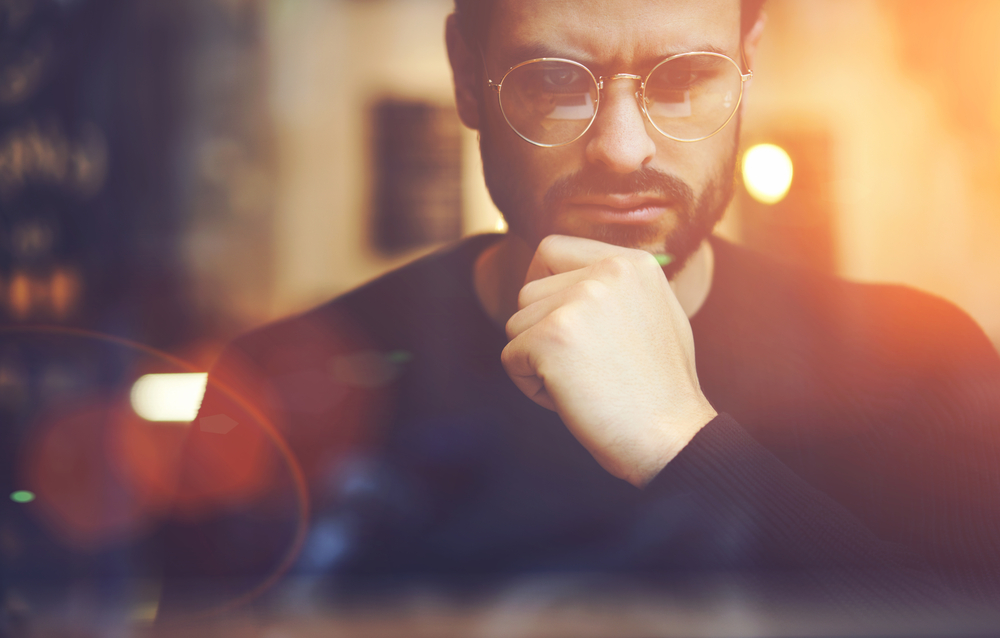 consider a non food fast Cropped close up image of pensive bearded entrepreneur in optical spectacles for better views dressed in black sweatshirt.Pondering businessman in trendy eyeglasses thinking on blurred background