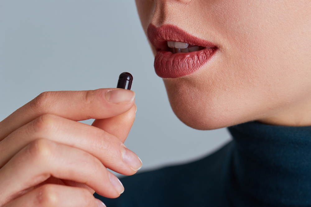 faulty advice Vitamin And Supplement. Closeup Of Beautiful Young Woman Taking Pill. Female Hand Putting Omega-3 Capsule In Mouth. Healthy Eating And Diet Nutrition.