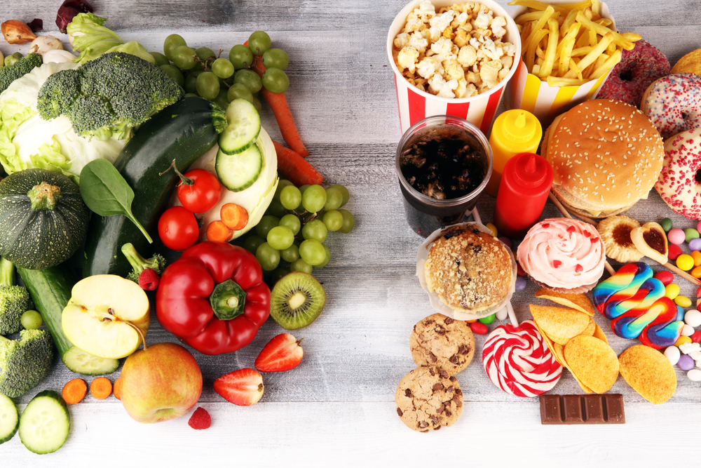 healthy or unhealthy food.reset the global food economy photo of healthy and unhealthy food. Fruits and vegetables vs donuts,sweets and burgers on table