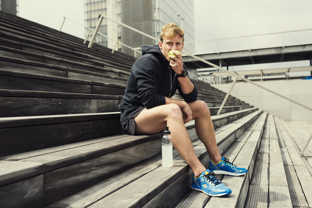 healthy metabolism Urban jogger heating a green apple after workout. City background