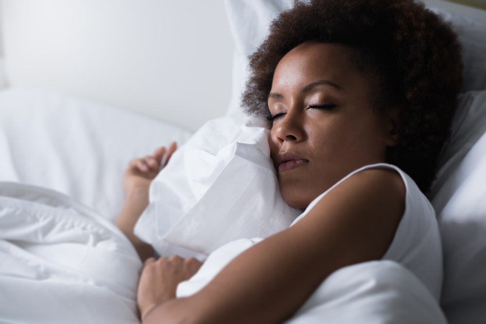 Why Sleep is important to weightloss Young african woman sleeping in her bed at night, she is resting with eyes closed